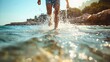 Low angle photography of a young man running or walking in sea, river or lake water on a sunny summer day. Youthful male person wearing shorts, splashing the water into air, ocean leisure activity