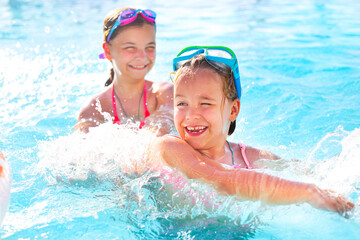 Two cute girls playing in swimming pool