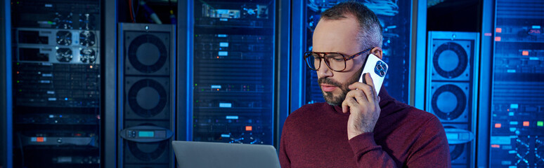 Wall Mural - devoted specialist in turtleneck talking by phone and looking at his laptop, data center, banner