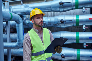 Wall Mural - concentrated technician in safety vest and yellow helmet outside of data center looking away