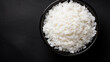 Bowl with boiled rice on dark background, top view. Space for text
