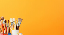 Creative Tools And Colors: Painting Brushes And Palettes On Orange Background
