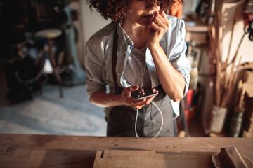 Wall Mural - Craftswoman listening to music in woodshop