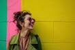 Young beautiful millennial woman smiling, standing near bright colorful vibrant yellow, pink, green wall with copy space