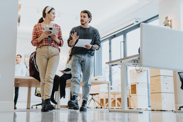 Young employees collaborate in a modern office, analyzing data, brainstorming ideas, and working together for business success while walking.