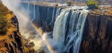 A breathtaking panorama captures the essence of Victoria Falls in Zimbabwe, where the waters thunder down, and a rare vertical rainbow graces the scene with its vibrant hues.