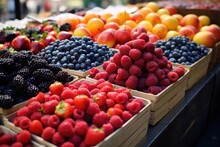  A Variety Of Fruits Are On Display At A Fruit Stand, Including Raspberries, Blueberries, Peaches, Strawberries, And Plums.
