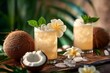 two glasses of coconut rum cocktail with leaves and flowers on a wooden