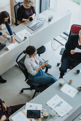 Wall Mural - High-angle shot of a diverse group of coworkers engaged in a collaborative work setting in a contemporary office. Teamwork and productivity in action as colleagues share ideas.