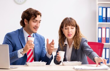 Wall Mural - Two colleagues having lunch break at workplace