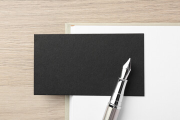 Sticker - Blank black business card, fountain pen and notebook on wooden table, top view. Mockup for design