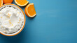 Cottage cheese in a bowl with oranges on a blue background, top view