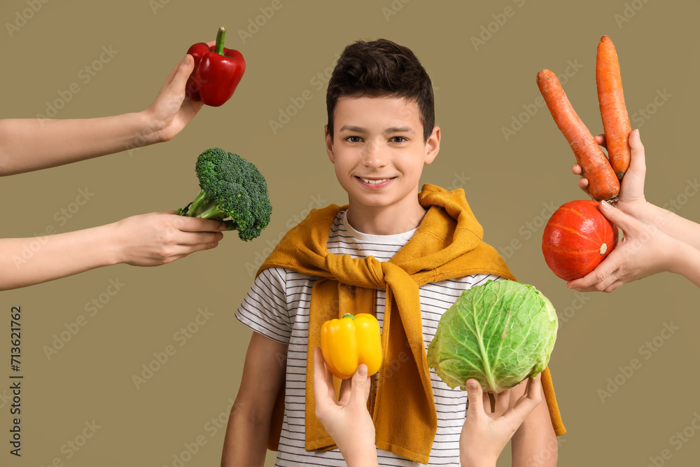 Cute little boy and hands with different vegetables on green background