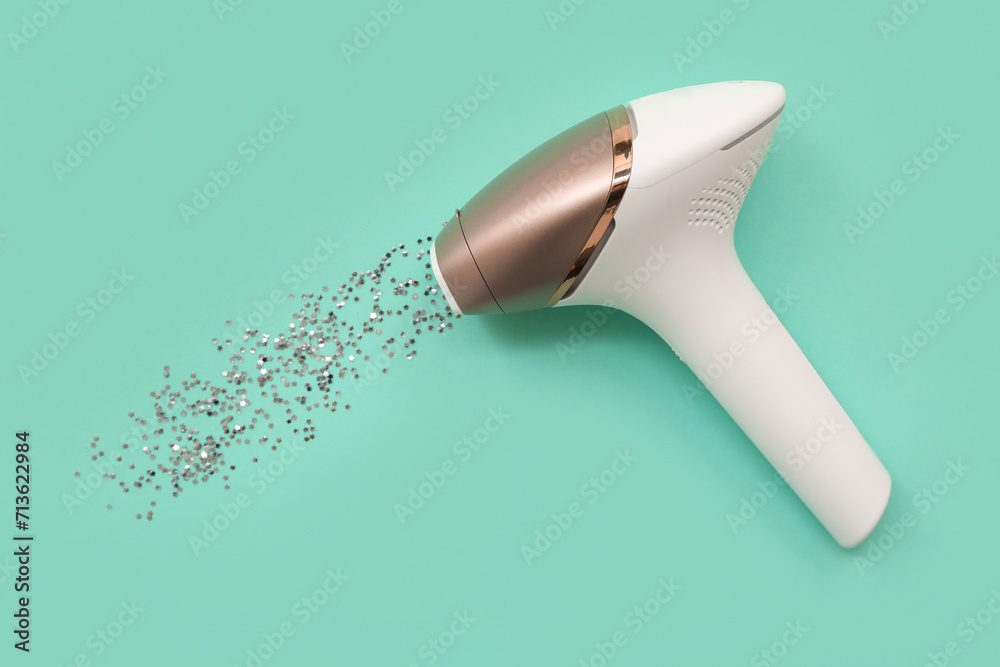 Modern photoepilator and sequins on color background