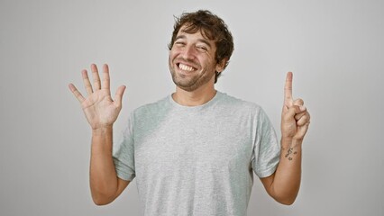 Poster - Cheerful young man, raising up his fingers, showing number six, smiling confidently in casual t-shirt. isolated white background. positive charming guy expression.