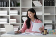 © Kainnika - Young beautiful asian businesswoman working with laptop and paperwork on desk in office.