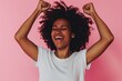 Joyful black woman celebrating success, pink background