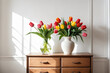 Vase with beautiful tulips flowers on chest of drawers near white wall