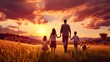 Family walking through field with sunset in the backround.