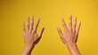 © Ramli - close up of two hands of a Man's Hand on a yellow background