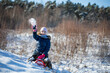 dziewczynka na sankach rzuca śnieżkami, zabawa na śniegu