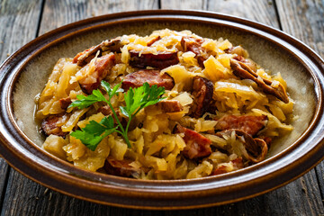 Poster - Cooked cabbage with sliced sausage on wooden table
