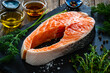 Fresh raw salmon steak with salt and fresh vegetables on wooden background
