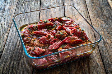 Poster - Raw pickled pork cheeks in heat-resistant dish on wooden table

