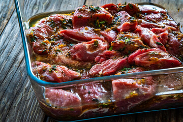 Wall Mural - Raw pickled pork cheeks in heat-resistant dish on wooden table

