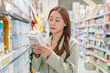 © Pormezz - woman reading nutrition label of product in supermarket