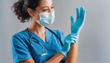 Female nurse with a face mask putting on gloves
