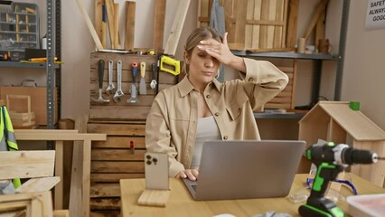 Poster - Stressed young blonde at carpentry studio, wrestling with laptop issues. her surprise and anger visible, frustration etching lines on her face.