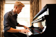© YannTouvay - Young man playing on grand piano at home. Music and leisure concept.