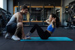 © Home-stock - Young fit couple working out at gym, man helping lady doing abs exercises with ball woman and handsome muscular guy training in dark modern gym