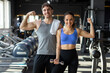 © Home-stock - Happy european man and woman posing in modern gym after their workout, showcasing their strong biceps and smiling at camera