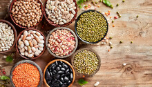 Top View Of Various Bowls Of Legumes Of Various Types And Colors On A Dark Wooden Kitchen Table. Healthy Food Concept And Detox Or Vegan Menu. World Pulses Day.
