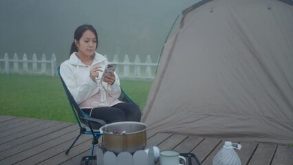 Wall Mural - Woman use cellphone beside the camp site