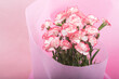 ピンクの背景のピンクの縁取りの白いカーネーションの花束のアップ
