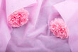 ピンクの紙の上のラッピングしたピンクのカーネーションの花