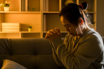 Sticker - Christian religious woman praying at night sitting on couch in living dark room at home. Human person hands worship, Concept of praying to God. Female prayer with holy bible. Lady thanksgiving night