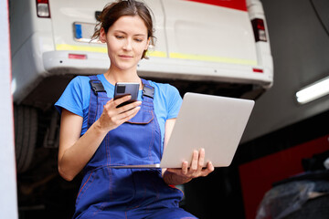 Poster - Woman auto mechanic with a laptop in car repair shop