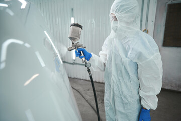 Wall Mural - Master paints the hood of a car with white paint