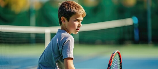 Young boy playing tennis on the green court.