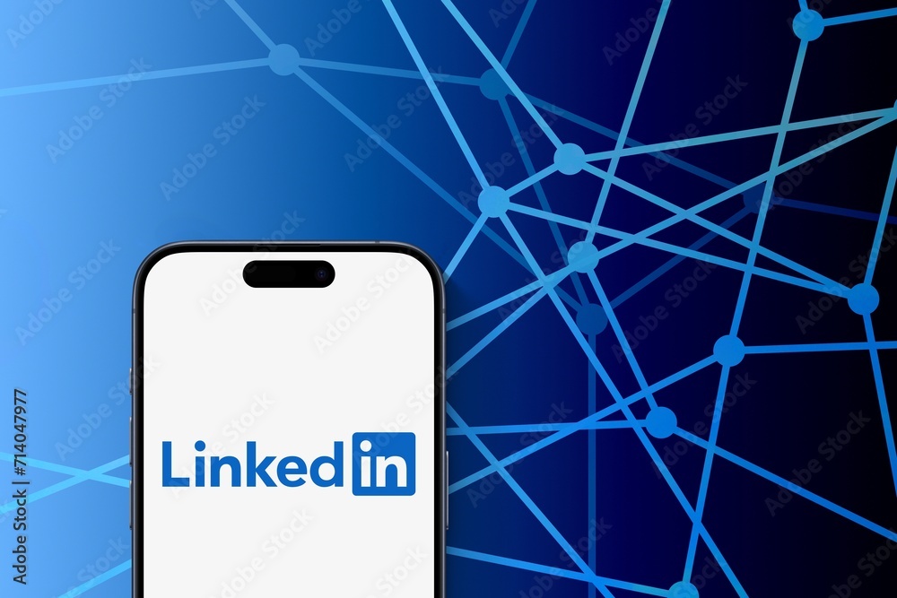 Linkedin logo is displayed on a modern smartphone, blue connected dots ...
