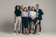 © gstockstudio - Happy young business team in formalwear looking at camera while standing on beige background