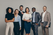 © gstockstudio - Happy young business team in formalwear looking at camera while standing on beige background