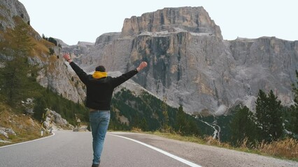 Wall Mural - Beautiful man traveler walks along mountain roads in the Dolomites. Incredibly beautiful views in the Alpine mountains. Route in the Alps mountains in autumn. Slow motion
