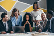 © gstockstudio - Smiling young business team looking at laptop while having group meeting in the office together