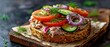 An everything bagel open-faced sandwich, generously topped with tuna salad, slices of ripe tomato, crisp cucumber, and purple onion rings, garnished with fresh dill,