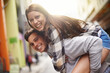Happiness, hug and portrait of couple piggyback ride for fun urban adventure, bonding and city journey. Wellness, embrace and young man, woman or people smile for relationship, goofy game or break